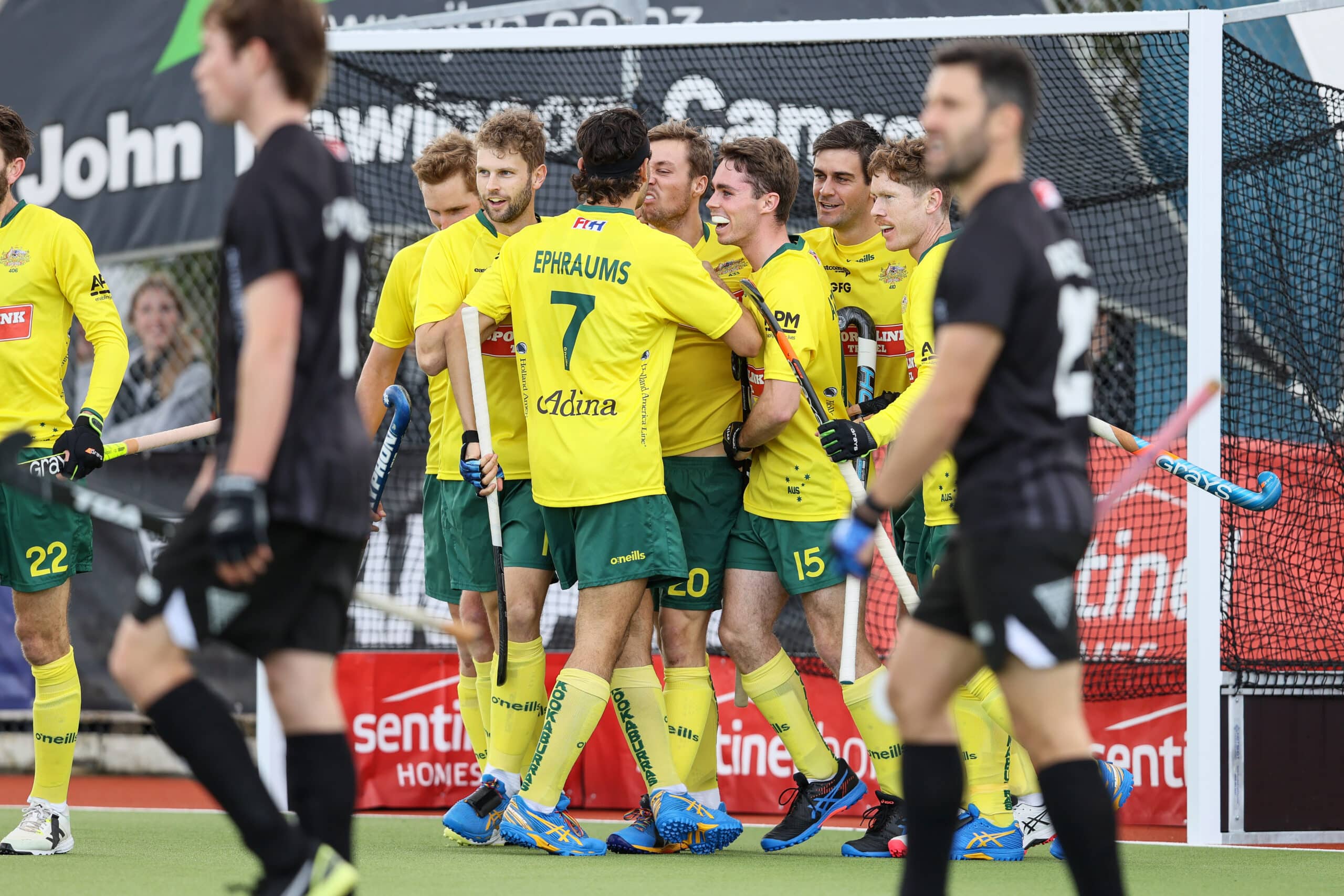 Australian hockey players in yellow compete on field during intense match action